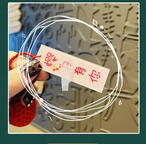 Détail macro d'un porte-clés en acrylique rose translucide avec cerises et dragonne rouge