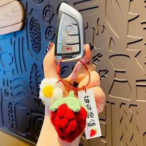 Porte-clés fraise au crochet fait main avec petite fleur blanche attaché à une clé