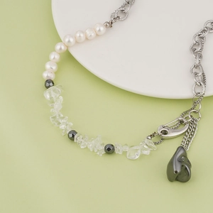 Dettaglio di una collana di perle industriali con pietra irregolare e catene in acciaio