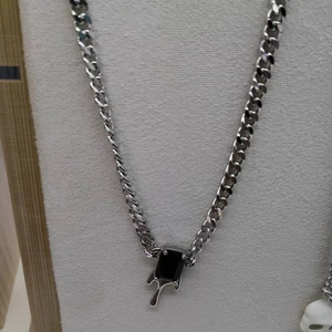 Detail of silver Cuban link chain featuring a black gemstone with liquid metal design
