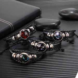Detailweergave van gelaagde leren armbanden met zodiac glas domes en punk kralen