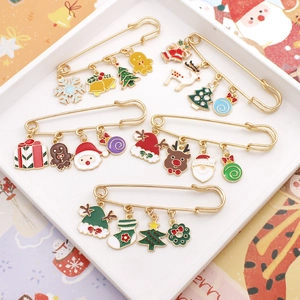 Detailed close-up of festive Christmas enamel charms on gold safety pin brooches