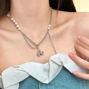 Close-up of a double-layered silver necklace with pink heart cherry pendants and pearls