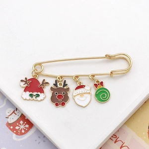 Macro view of Christmas brooch with hanging Santa, reindeer, and tree charms