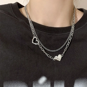 Close-up of layered silver heart necklaces with crystals on a black t-shirt model view