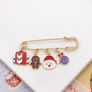 Detail of Christmas safety pin brooch with hanging gingerbread man and Santa charms