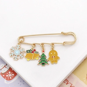 Close-up of Christmas safety pin brooch with charms including snowflake and gingerbread man