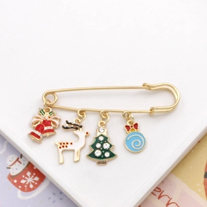 Detailed close-up of gold safety pin brooch with colorful Christmas tree and reindeer charms