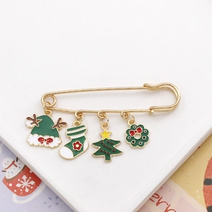 Detail view of a gold Christmas brooch featuring enamel reindeer, tree, and wreath charms