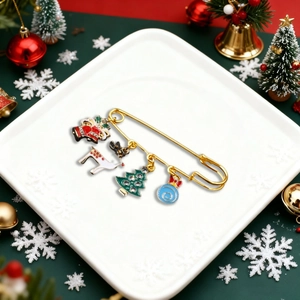 Christmas safety pin brooch with enamel charms of reindeer and tree on white plate