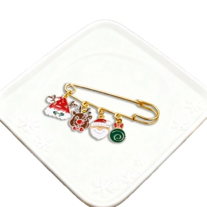 Christmas brooch pin with festive charms including Santa Claus and reindeer on white plate