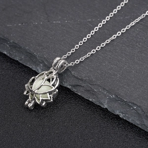 Vue détaillée d'un pendentif lotus évidé avec une perle lumineuse verte sur fond de pierre