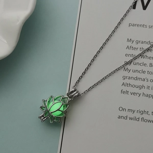Détail du pendentif lotus ajouré avec perle verte lumineuse sur une chaîne argentée