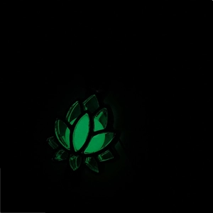 Gros plan d'un pendentif lotus évidé lumineux avec effet de lueur verte