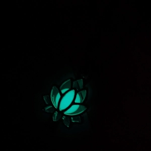 Détail du pendentif lotus ajouré avec perle lumineuse cyan brillant dans l'obscurité