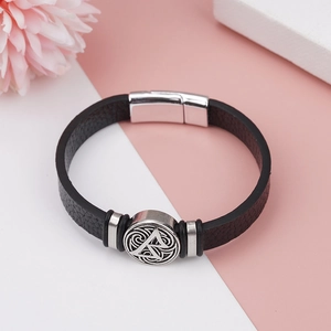 Detail of Viking Valknut engraved medallion on a woven black leather bracelet for men