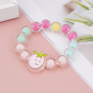 Dettaglio del braccialetto per bambini in perle acriliche con ciondolo a fragola