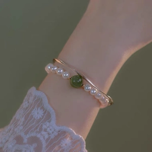 Macro-opname van parelarmband met groene edelsteen en elegante gouden armband