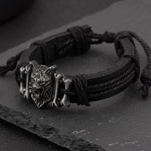 Detail of multi-layer black braided leather bracelet featuring a silver metal wolf head
