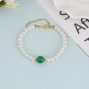 Elegante parelarmband met een grote groene kraal en gouden verstelbare ketting op blauw