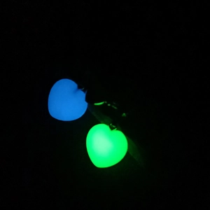 Close-up of heart-shaped luminous pendants glowing in vibrant blue and green colors