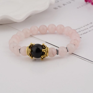 Detailed close-up of pink crystal beads with a golden crown charm on an elegant bracelet