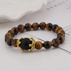 Macro detail of men's tiger eye bead bracelet with golden crown alloy charms
