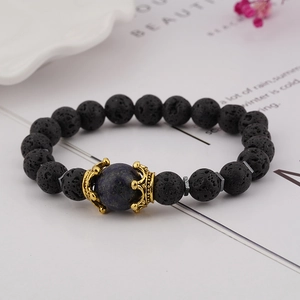 Close-up of black lava stone bracelet with blue lapis lazuli bead and golden crown charm