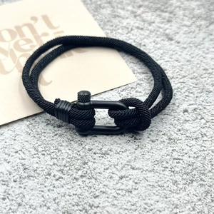 Détail du bracelet en corde milanaise noire avec un fermoir en U en métal noir robuste