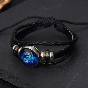 Detail of multi-layer leather bracelet featuring a luminous Virgo zodiac glass charm