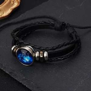 Macro shot of multi-layer leather bracelet featuring glowing zodiac glass dome pendant