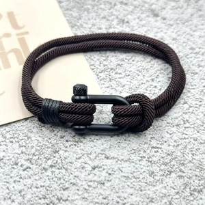 Détail du bracelet tressé marron foncé avec boucle en U métallique noire mate