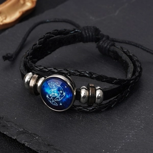 Macro detail of braided leather bracelet featuring a luminous zodiac glass charm and beads