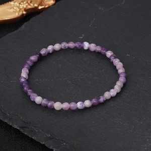 Natural 4mm purple stone energy bead bracelet on a dark slate background