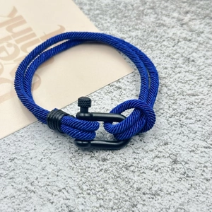 Détail d'un bracelet en nylon tressé bleu avec manille en métal noir mat en forme de U
