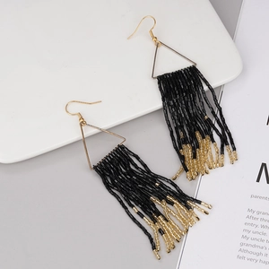 Detail shot of bohemian handmade bead tassel earrings with golden triangle frame