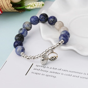 Détail du bracelet en perles de pierre bleue avec breloque cœur sur plateau