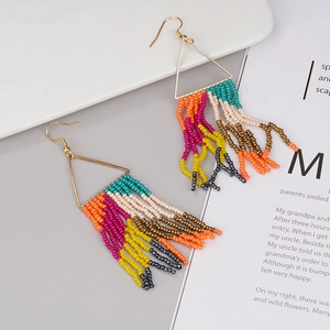 Detail of bohemian handmade beaded fringe earrings with colorful beads and gold triangle hooks