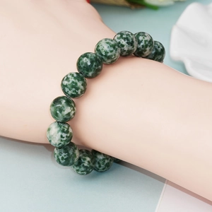 Bracelet en perles de pierre naturelle tachetée verte sur main avec décor épuré