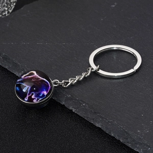 Constellation glass ball keychain with Taurus galaxy pattern on black stone background