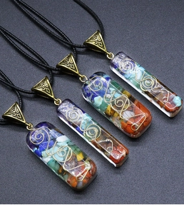 Detailed macro view of four rectangular Orgone chakra pendants with colorful stones and metal coils