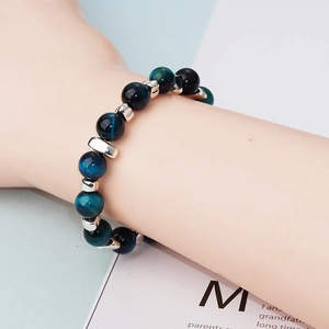 Bracelet en œil de tigre bleu et perles noires avec séparateurs argentés sur poignet masculin