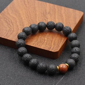 Gros plan sur les perles en pierre volcanique noire et l'entretoise dorée du bracelet homme
