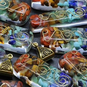 Handmade resin pendant with colorful natural stones and spiral wire on dark background