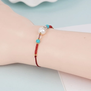 Detail of handmade woven bracelet with a large white freshwater pearl and crystal beads