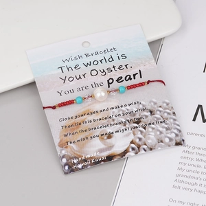 Detail of handmade red woven wish bracelet with freshwater pearl and decorative beads