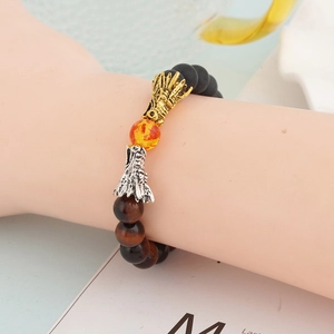 Detail of dragon head charms on tiger eye and volcanic stone beaded bracelet