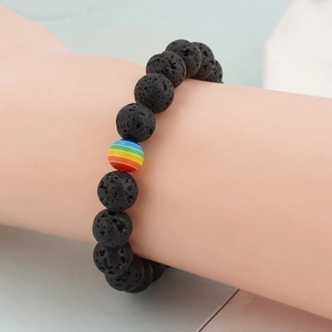 Black lava rock beaded bracelet with rainbow stone accent worn on a male wrist