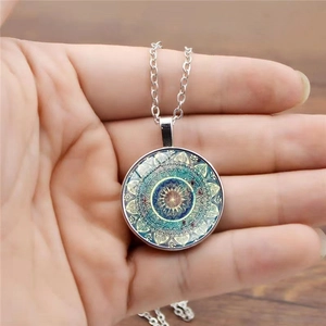 Vintage mandala glass pendant necklace with silver chain shown in a hand-held view