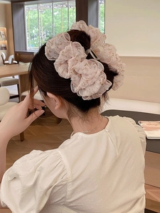 Dettaglio di un grande fermaglio per capelli in organza rosa a fiori indossato da una modella